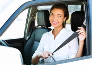 Attractive young woman in a car fastens seat belt