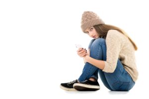 Teenage girl holding cell phone looking scared